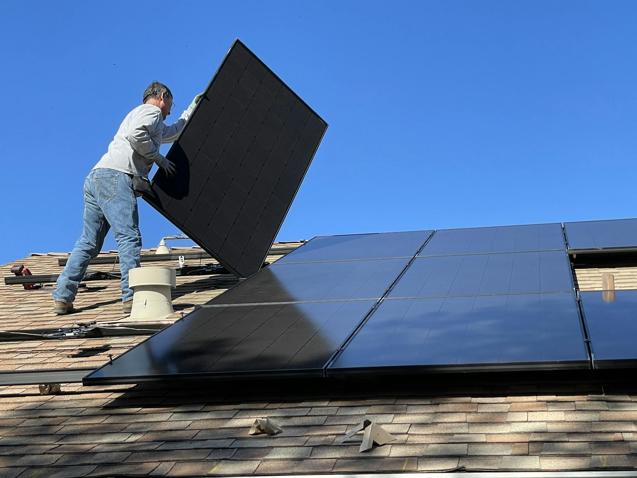 A worker installs solar panels on a sunny day, highlighting renewable energy solutions.